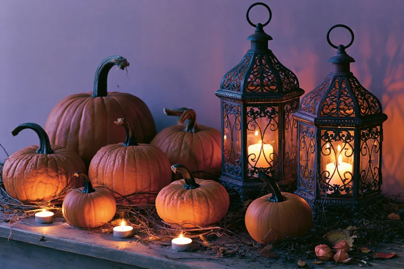 Pumpkins and lanterns with candles arranged on a wooden table for halloween decoration