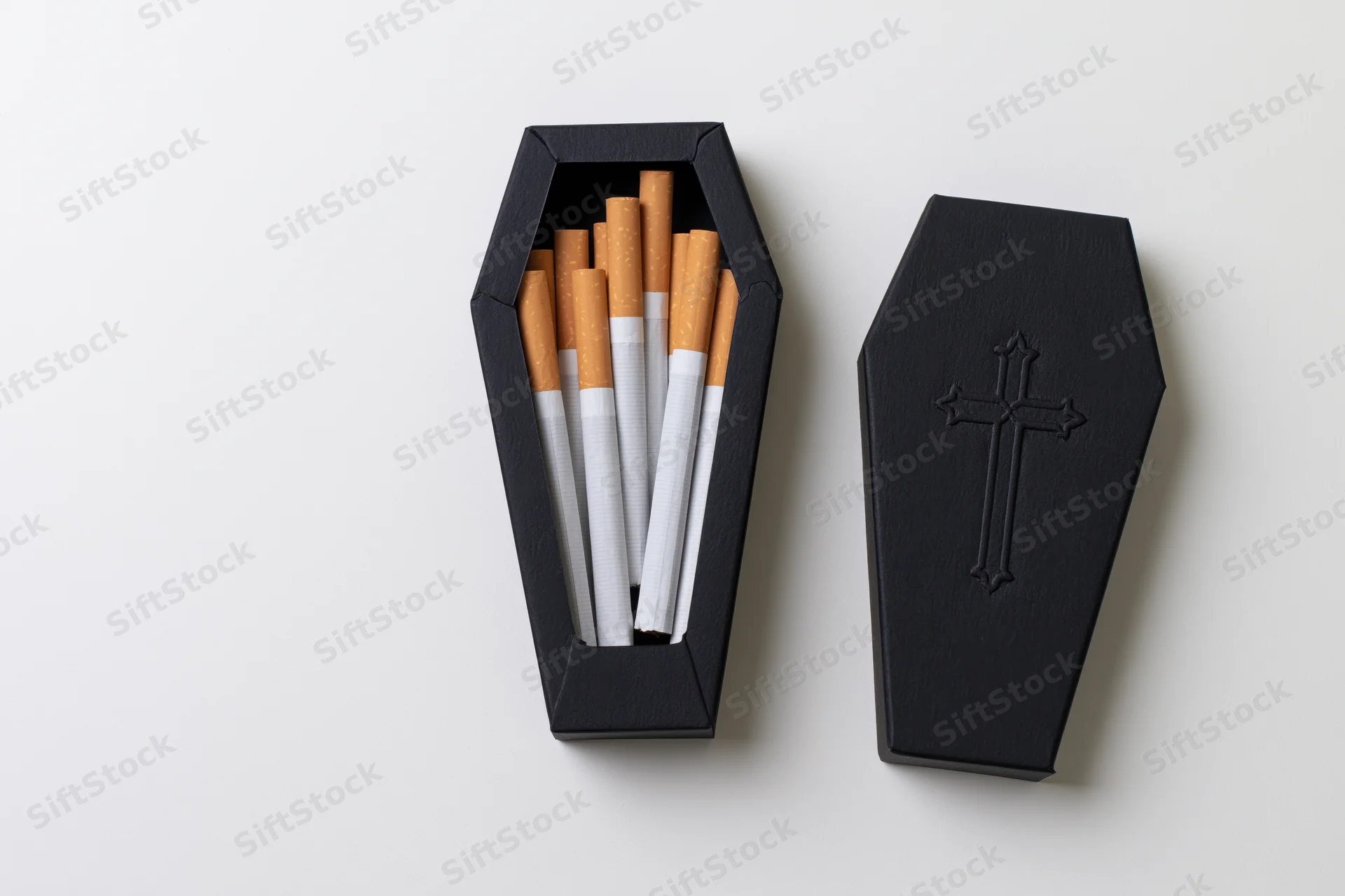 Open black coffin-shaped box filled with cigarettes on white background