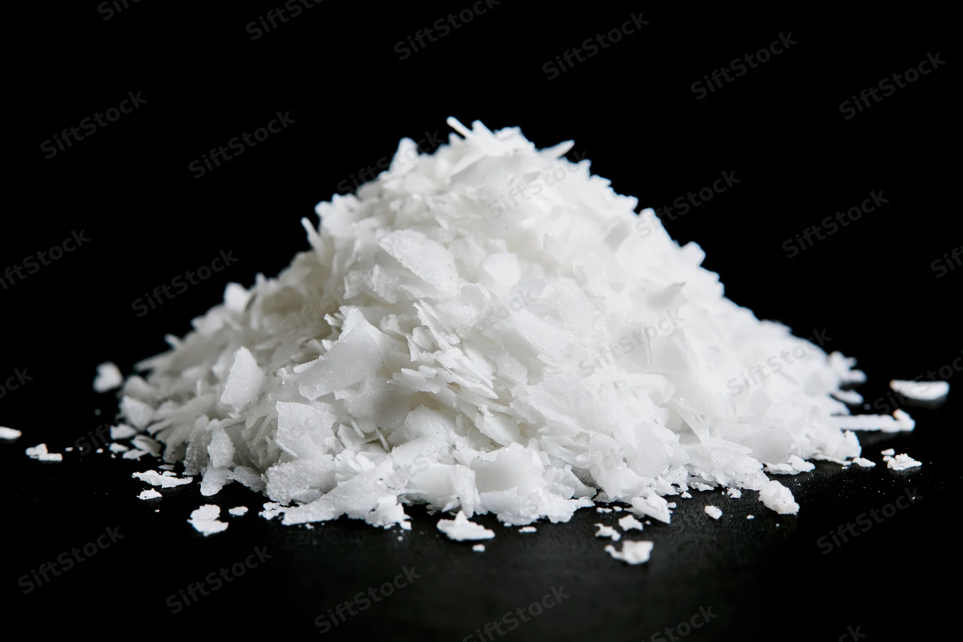 Pile of white coconut flakes on black background