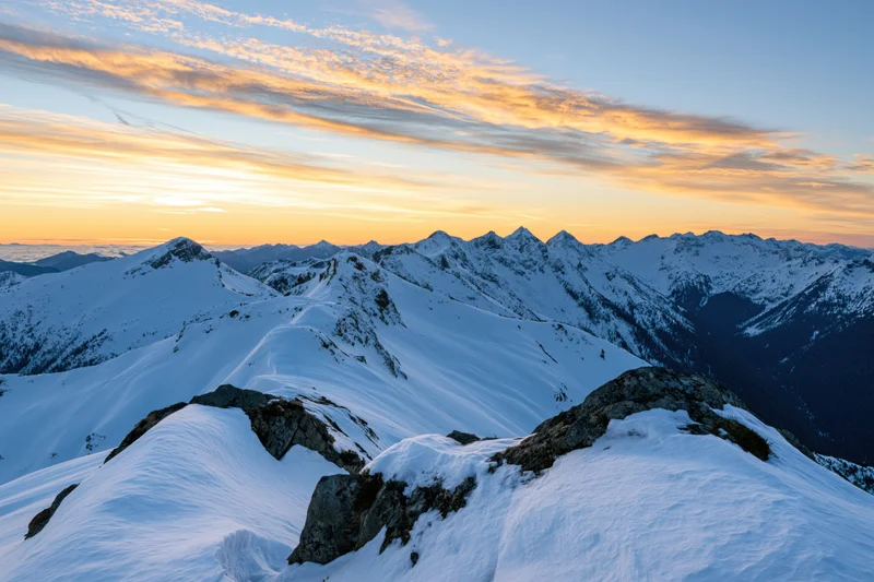 Snow-covered alpine mountain range viewed from a high ridge at sunset