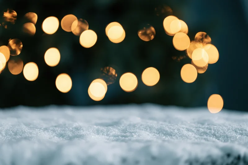 Snow-covered surface with blurred golden lights in the background at night