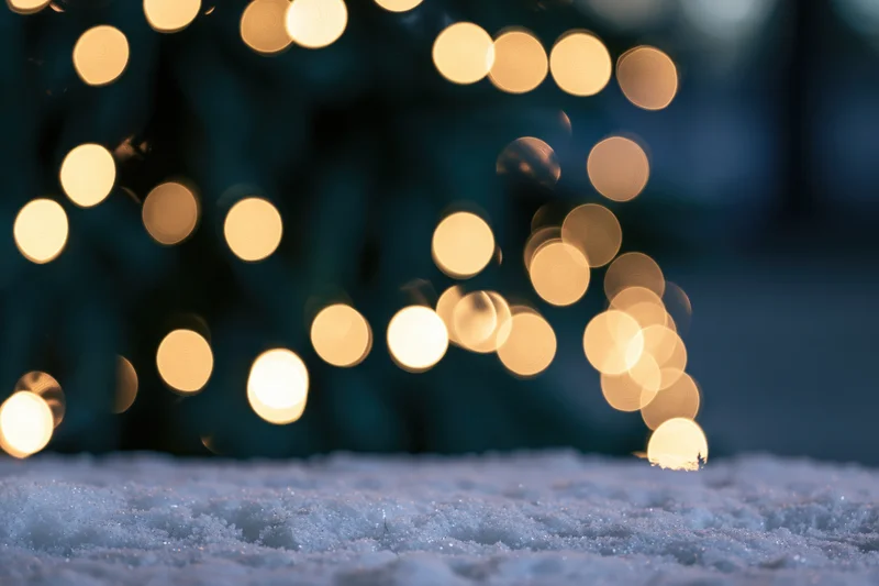 Snow-covered ground with blurred golden lights in the background during winter night