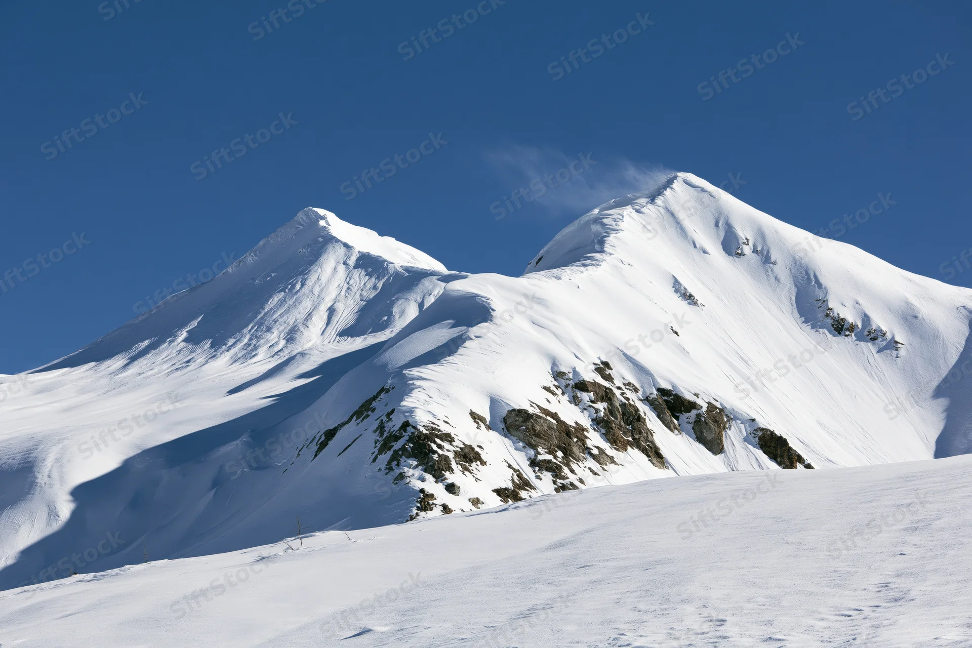 Snow-covered twin mountain peaks rising against a clear deep blue sky