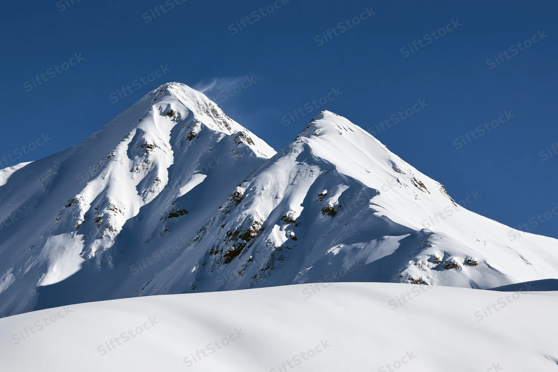 Snow-covered twin mountain peaks rising against a clear deep blue sky