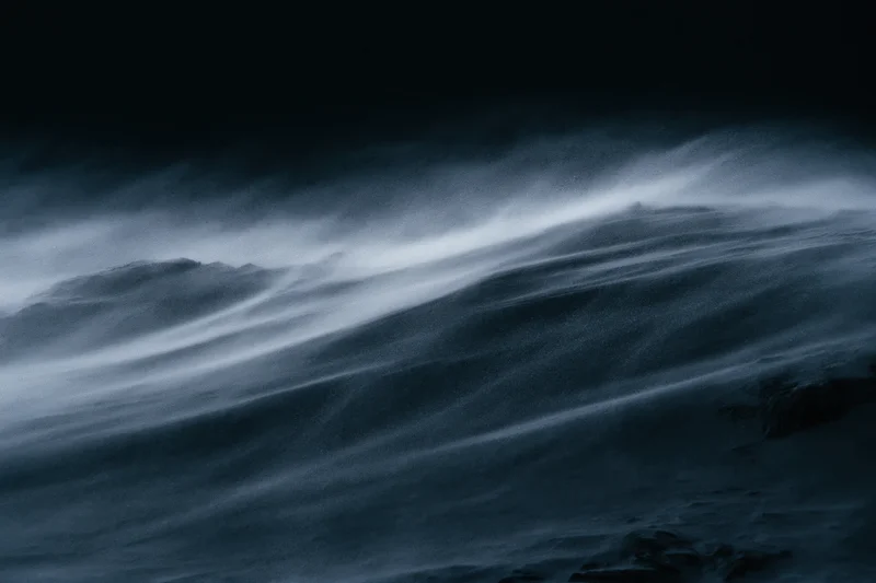 Snow swept across a dark mountain ridge in a storm