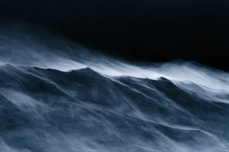 Snow swept across dark mountain ridge in stormy winter night