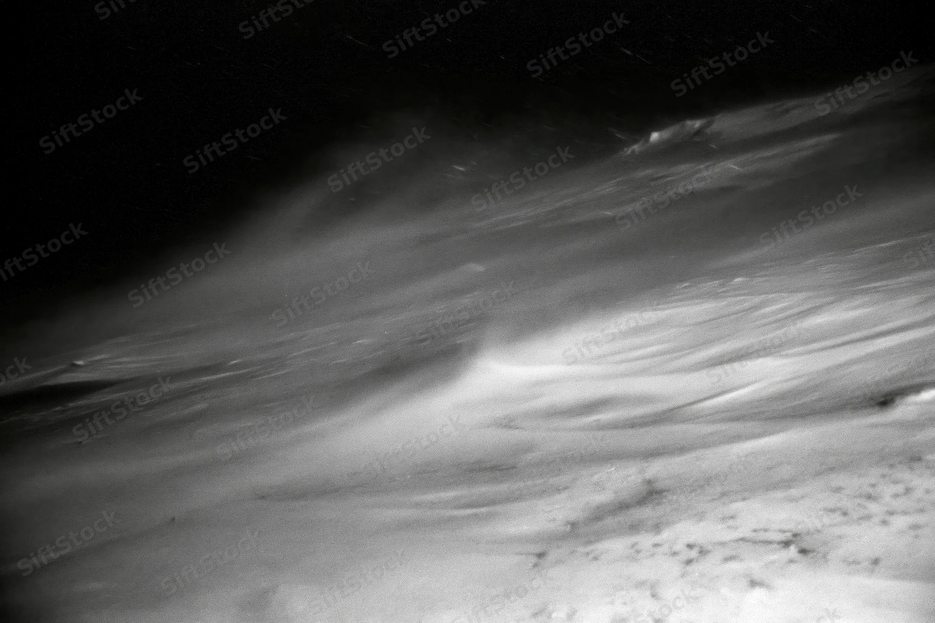 Snow blowing violently across a high-alpine ridge at night