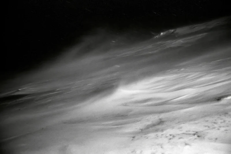 Snow blowing violently across a high-alpine ridge at night