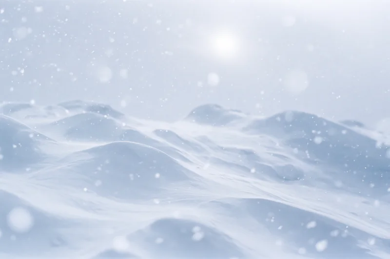 Snow-covered landscape with drifting snow under bright sun, winter scene