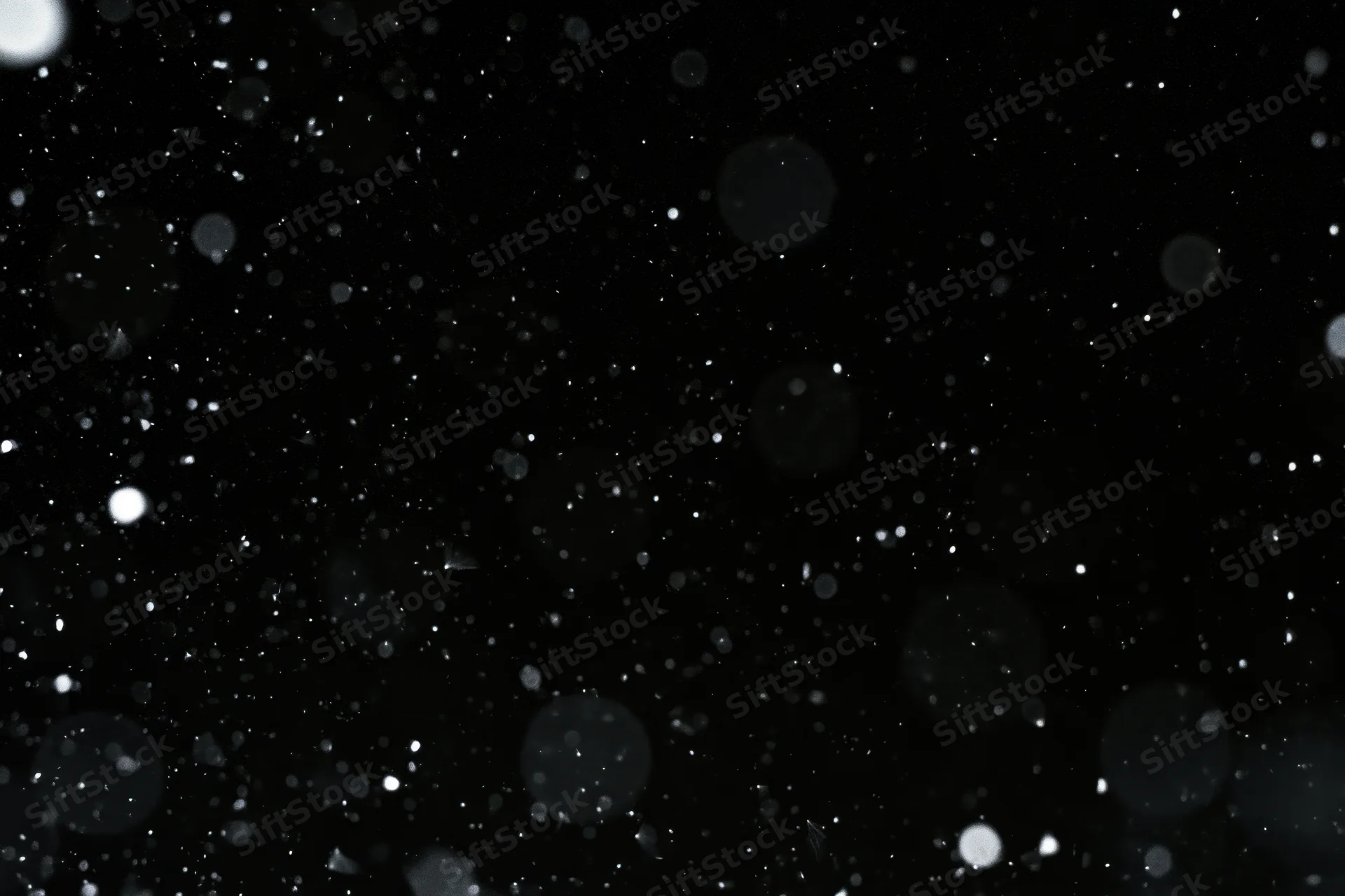 Snow and dust particles falling against a black background