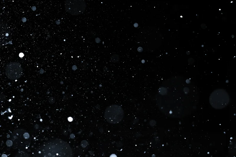 Snow and dust particles falling against a pure black background