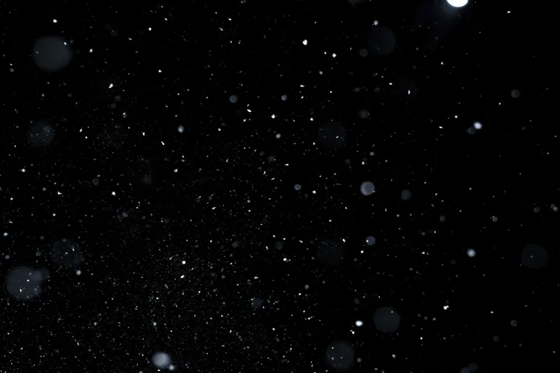Snow and dust particles floating in midair against a black background