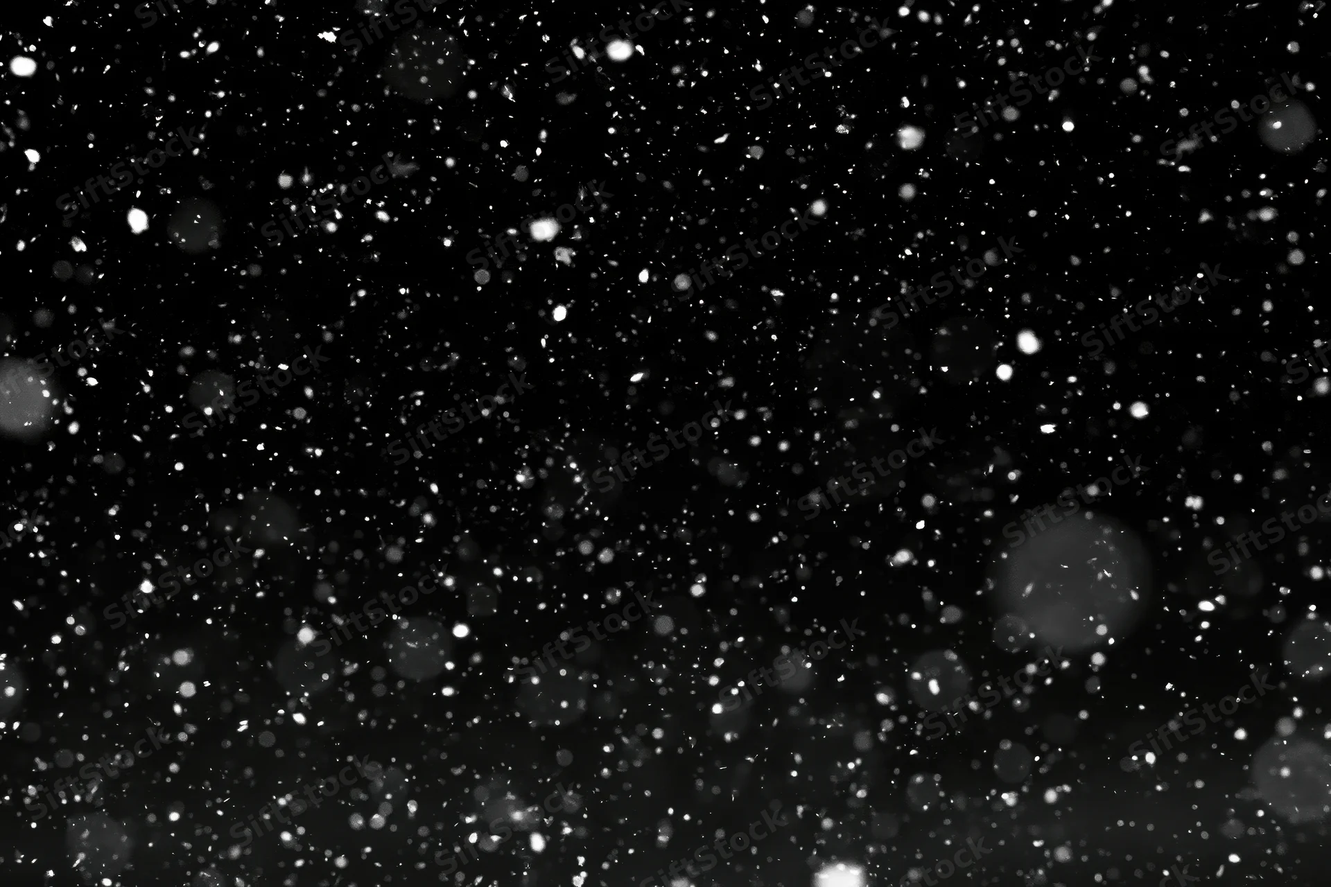Snow particles falling against a black night sky
