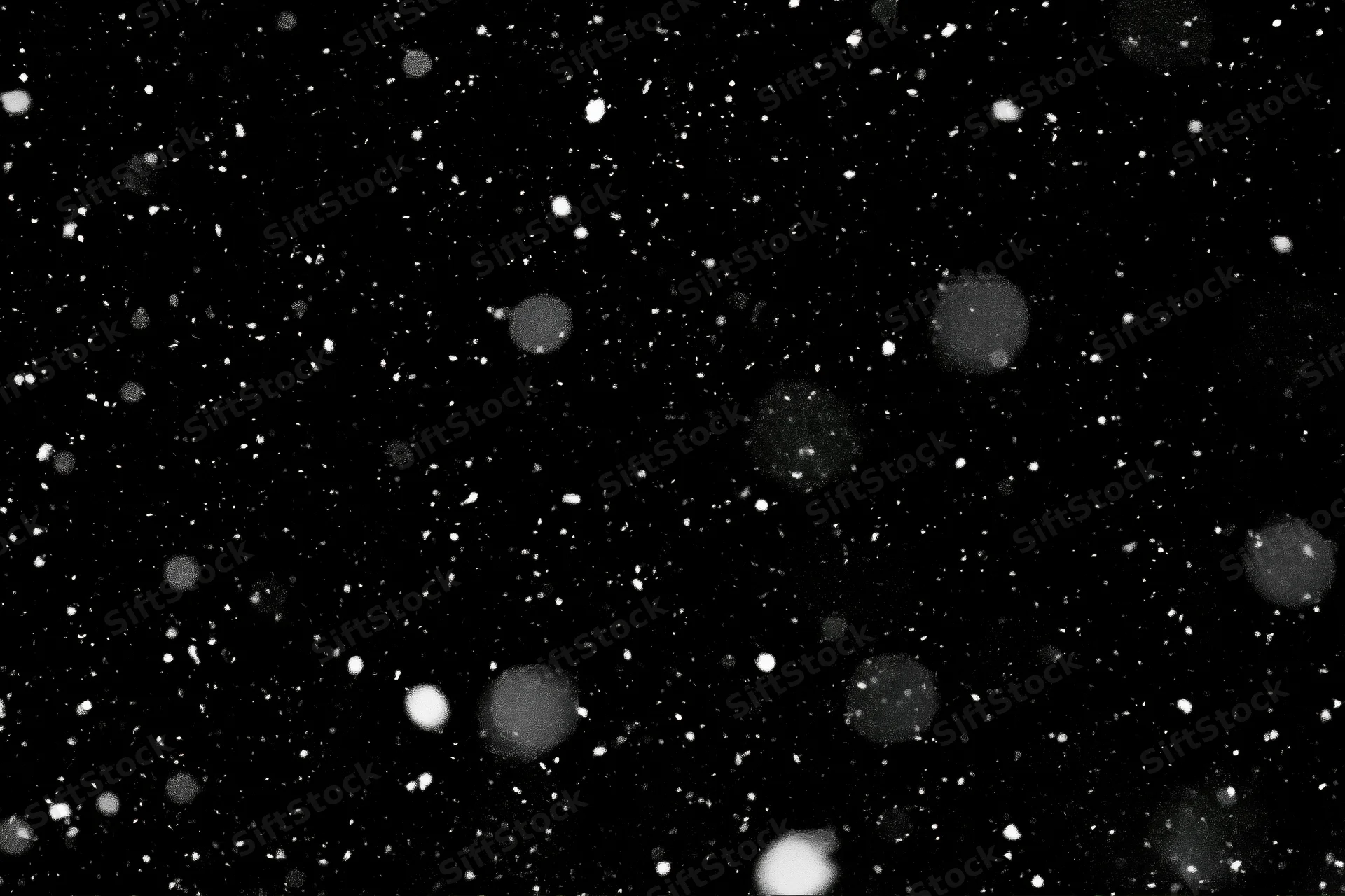 Snow particles falling against a pure black night sky