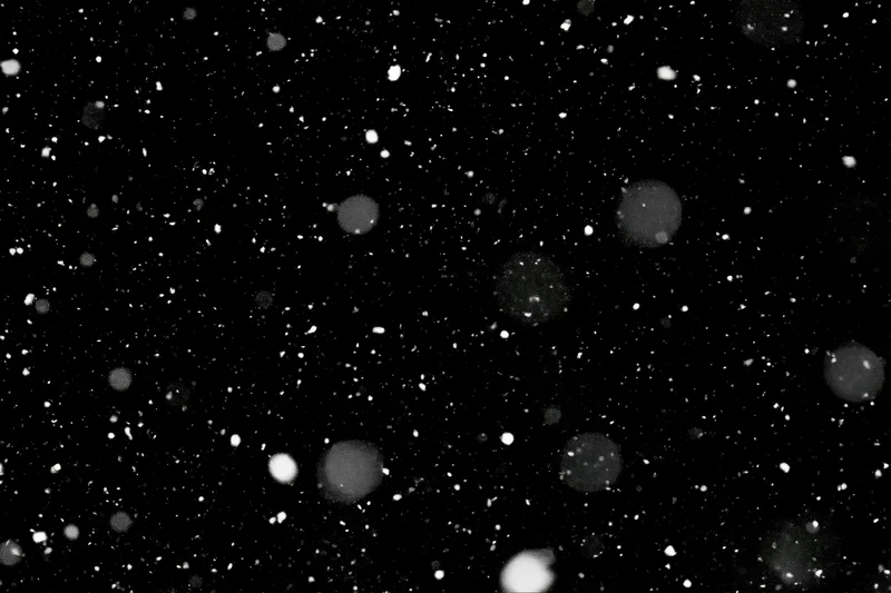 Snow particles falling against a pure black night sky