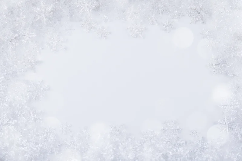 Snowflakes arranged in a border around a blank white center with soft bokeh lights