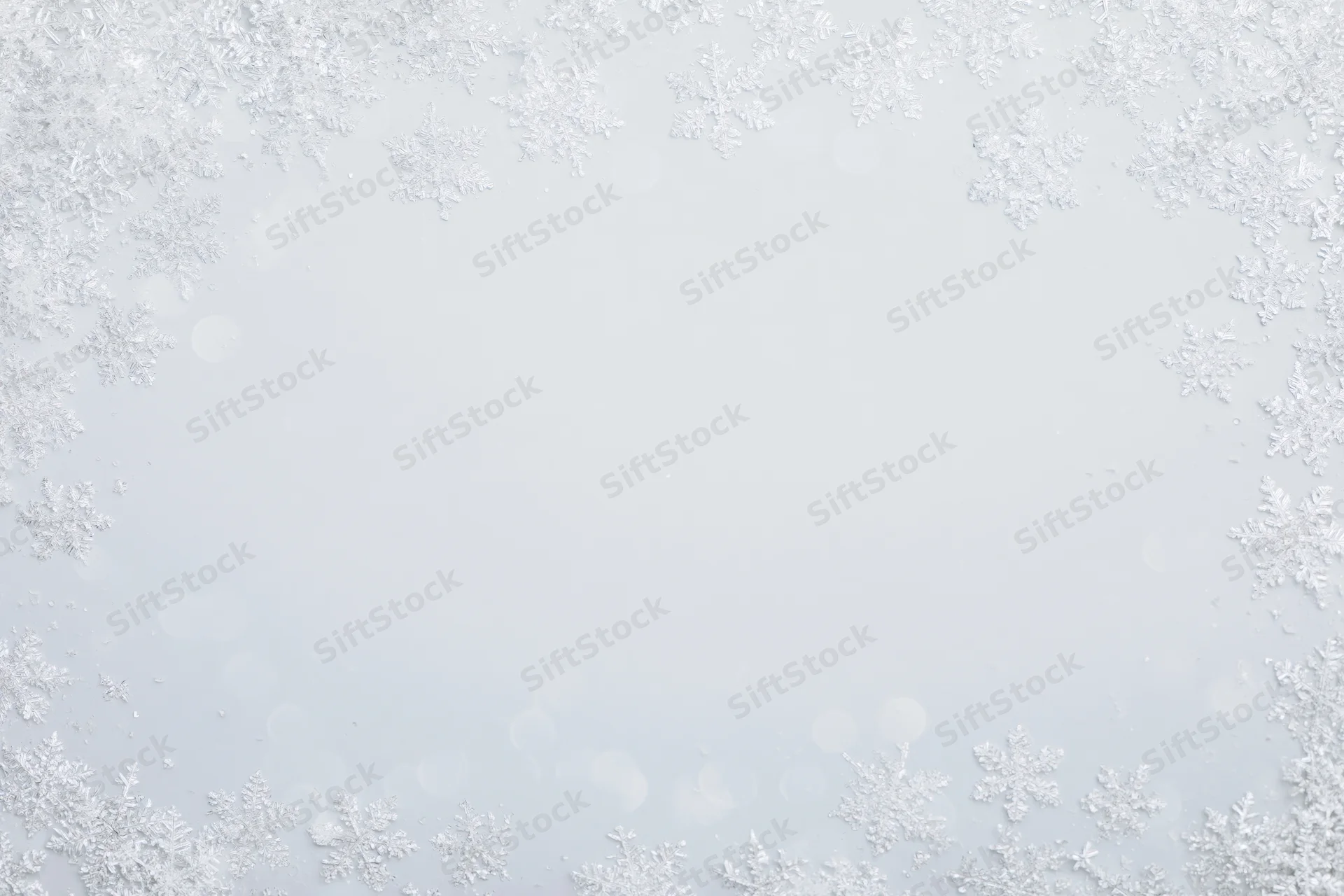 Snowflakes arranged in a border around a soft white background with bokeh light effects