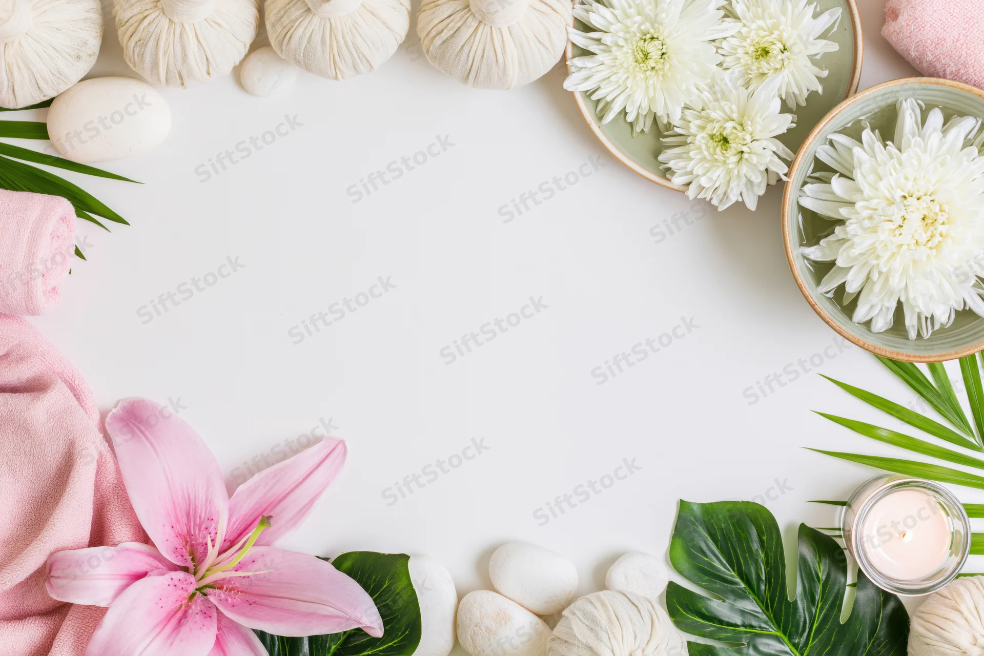 Spa wellness flat lay arranged as a top-and-bottom border with flowers, towels, stones, and leaves on white surface