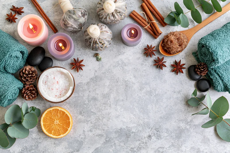 Spa wellness flat lay with candles, herbs, towels and bath products on textured grey concrete surface