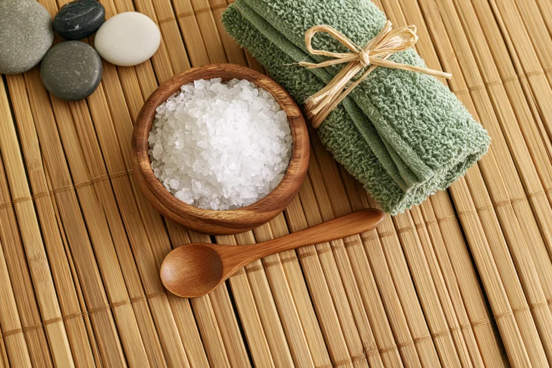 Spa wellness flat lay with salt, towel, stones and wooden spoon on bamboo mat