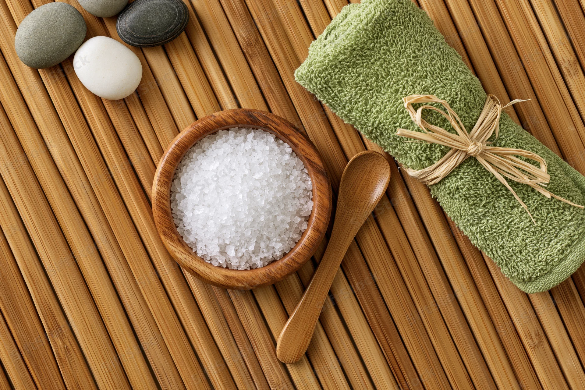 Spa wellness flat lay with salt, towel and stones on bamboo mat