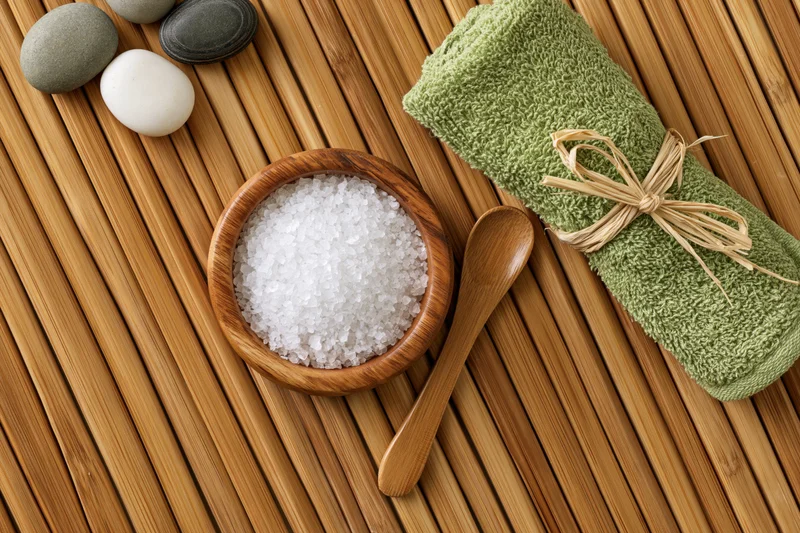 Spa wellness flat lay with salt, towel and stones on bamboo mat