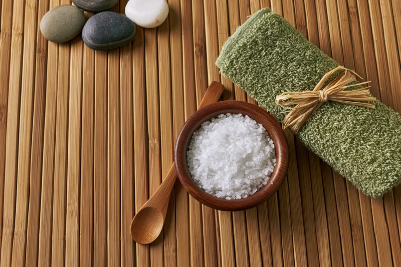 Spa wellness flat lay with salt, towel, stones and wooden bowl on bamboo mat