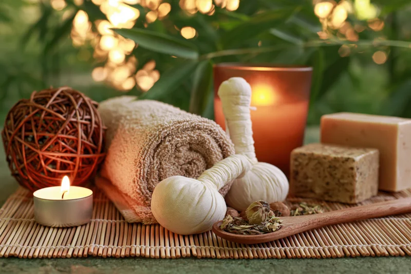 Spa wellness still life with candles, towel, soap, and herbs on bamboo mat