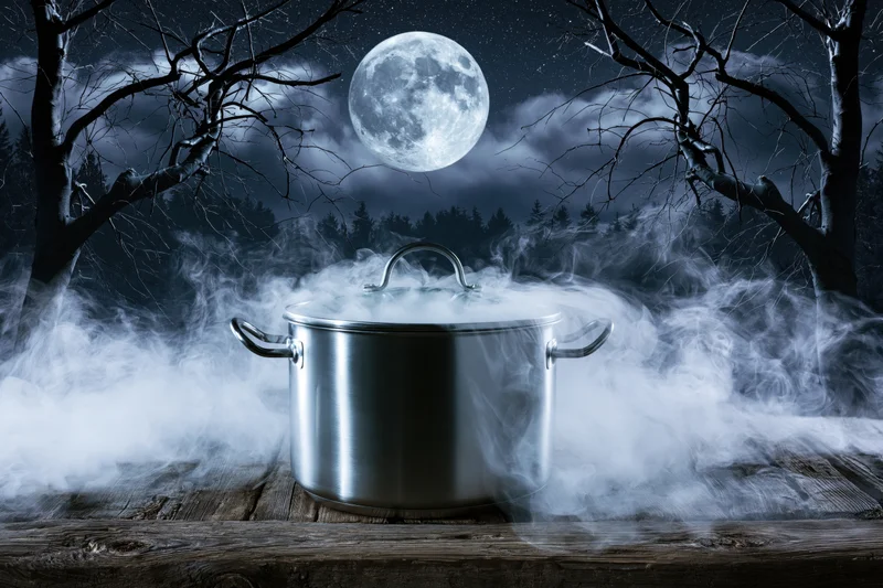 Stainless steel pot steaming on wooden table under full moon in dark forest