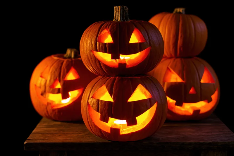 Carved pumpkins glowing with candlelight arranged on a wooden table for Halloween