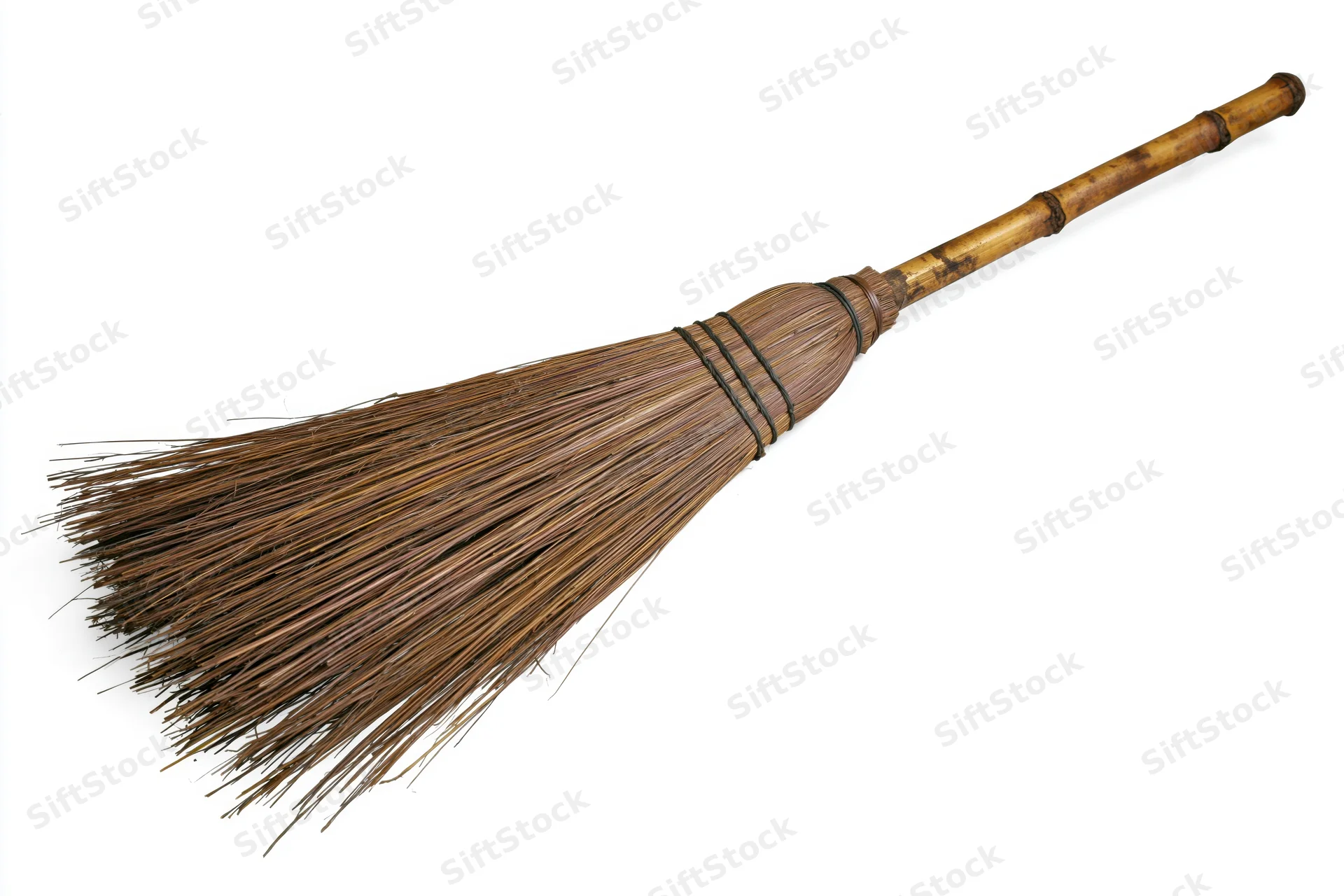 Traditional straw broom with worn bamboo handle lying on white background