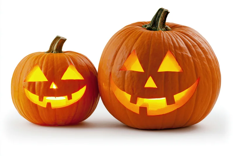 Two carved pumpkins glowing with light side by side on white