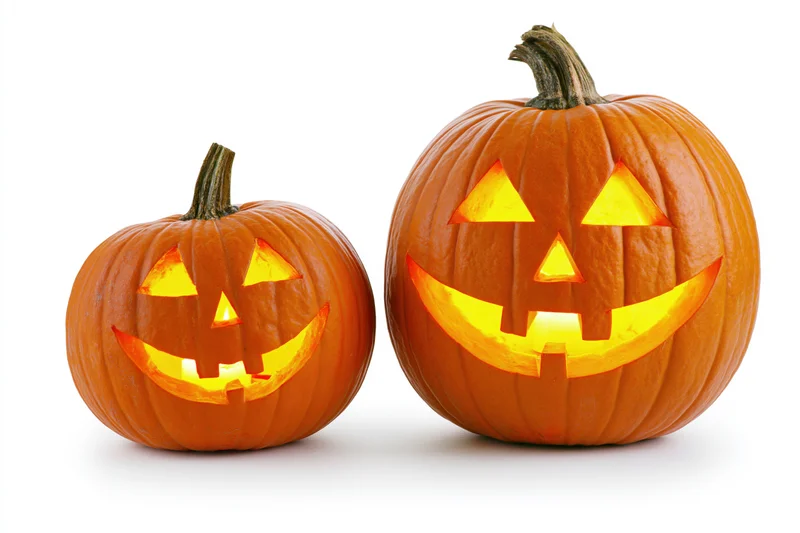 Two carved pumpkins glowing with light side by side on white