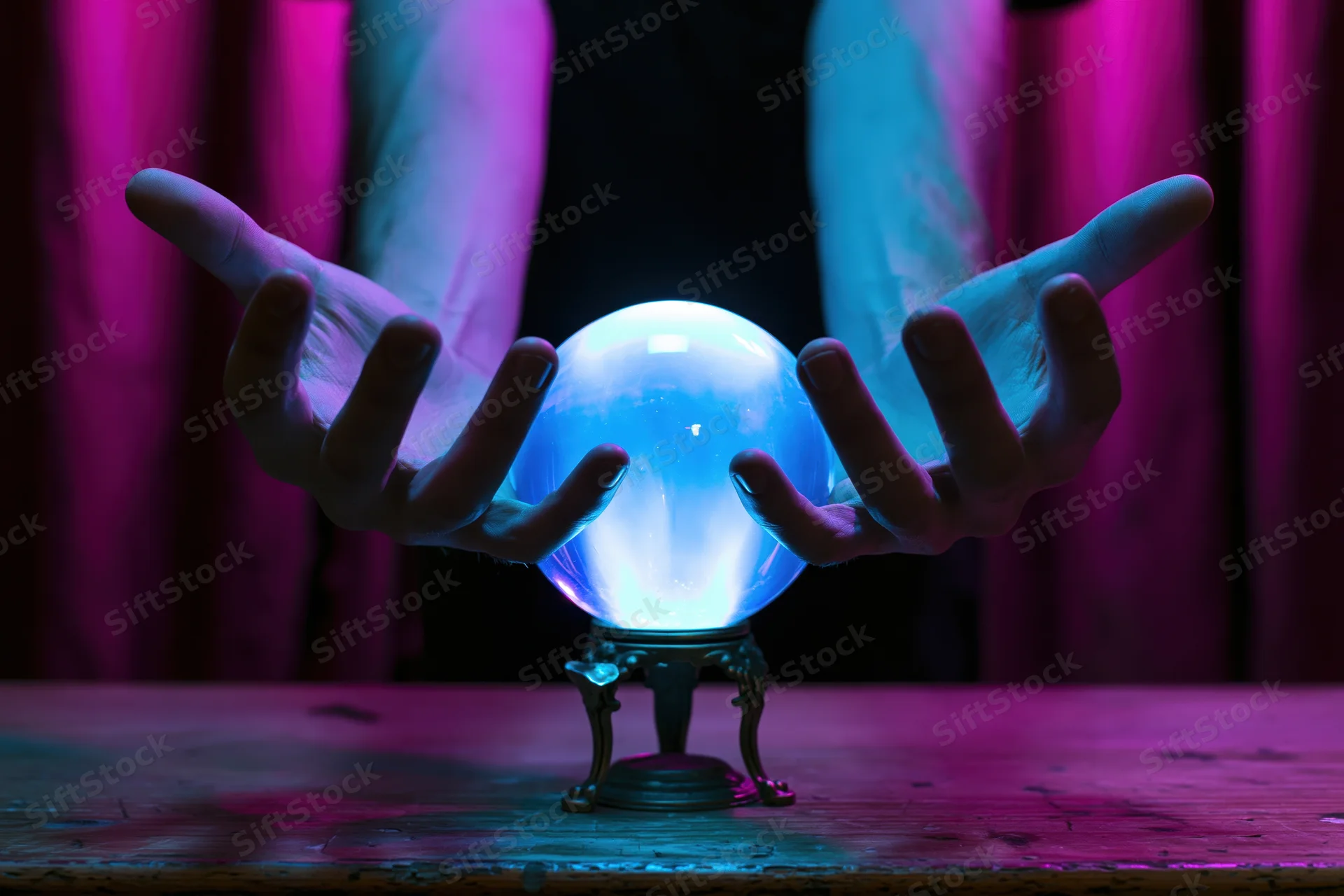Hands hovering over a glowing blue crystal ball on a wooden table with purple curtains in the background
