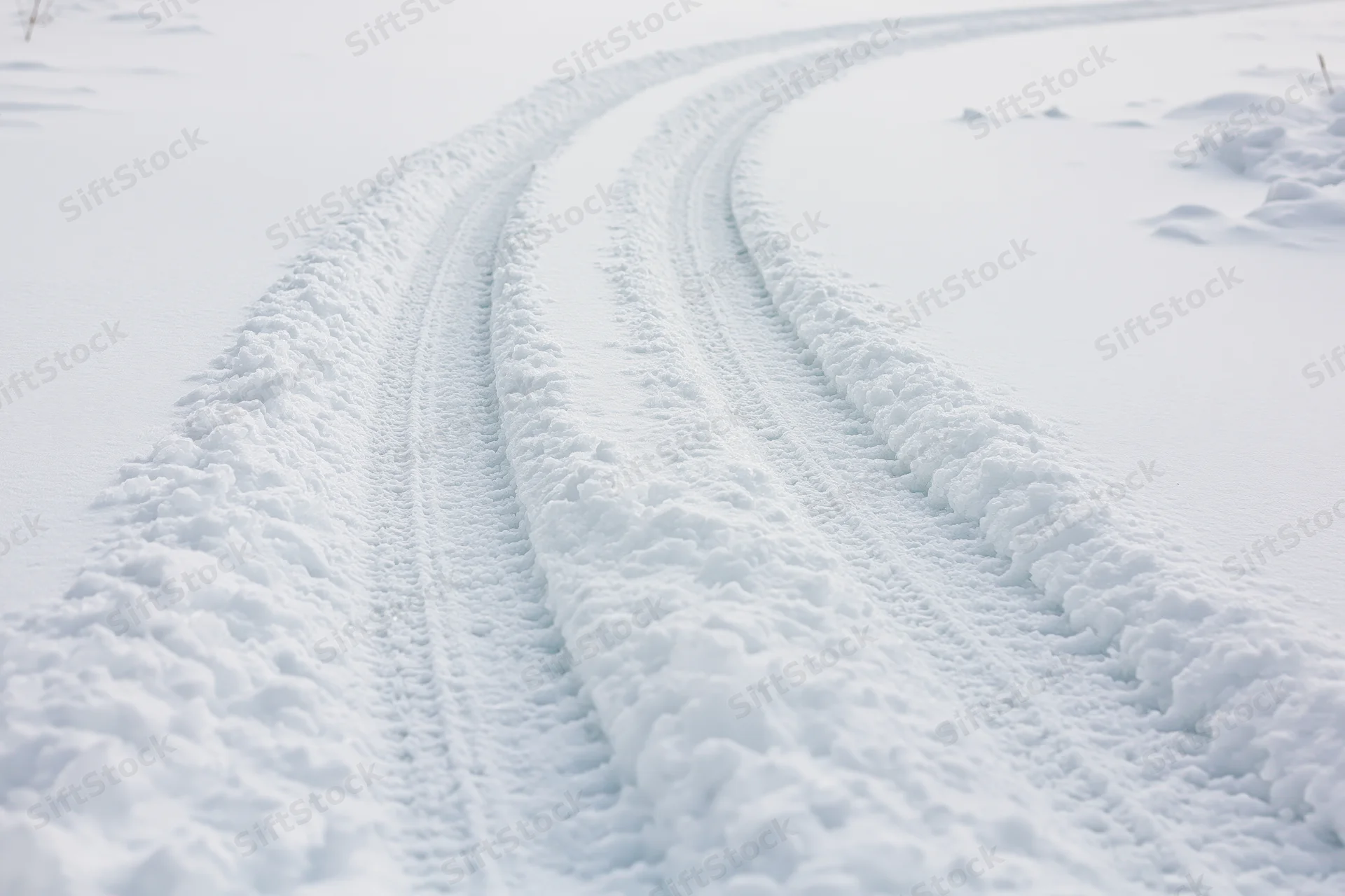 Tire tracks curving through deep snow in a winter landscape