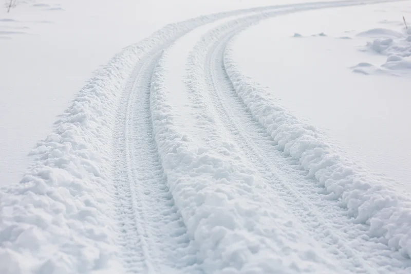 Tire tracks curving through deep snow in a winter landscape