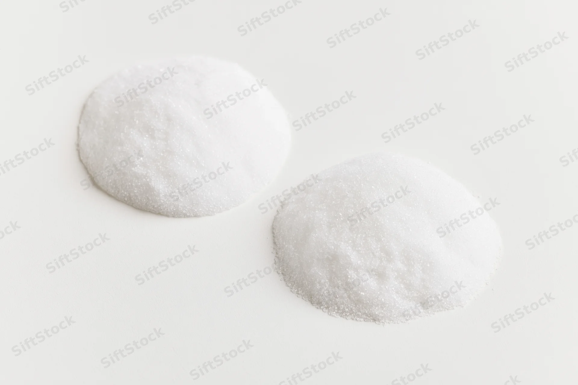 Two mounds of fine white crystalline powder on a plain white surface