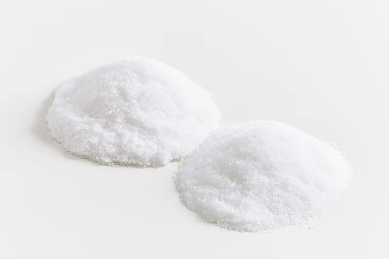 Two mounds of fine white crystalline powder on a plain white surface