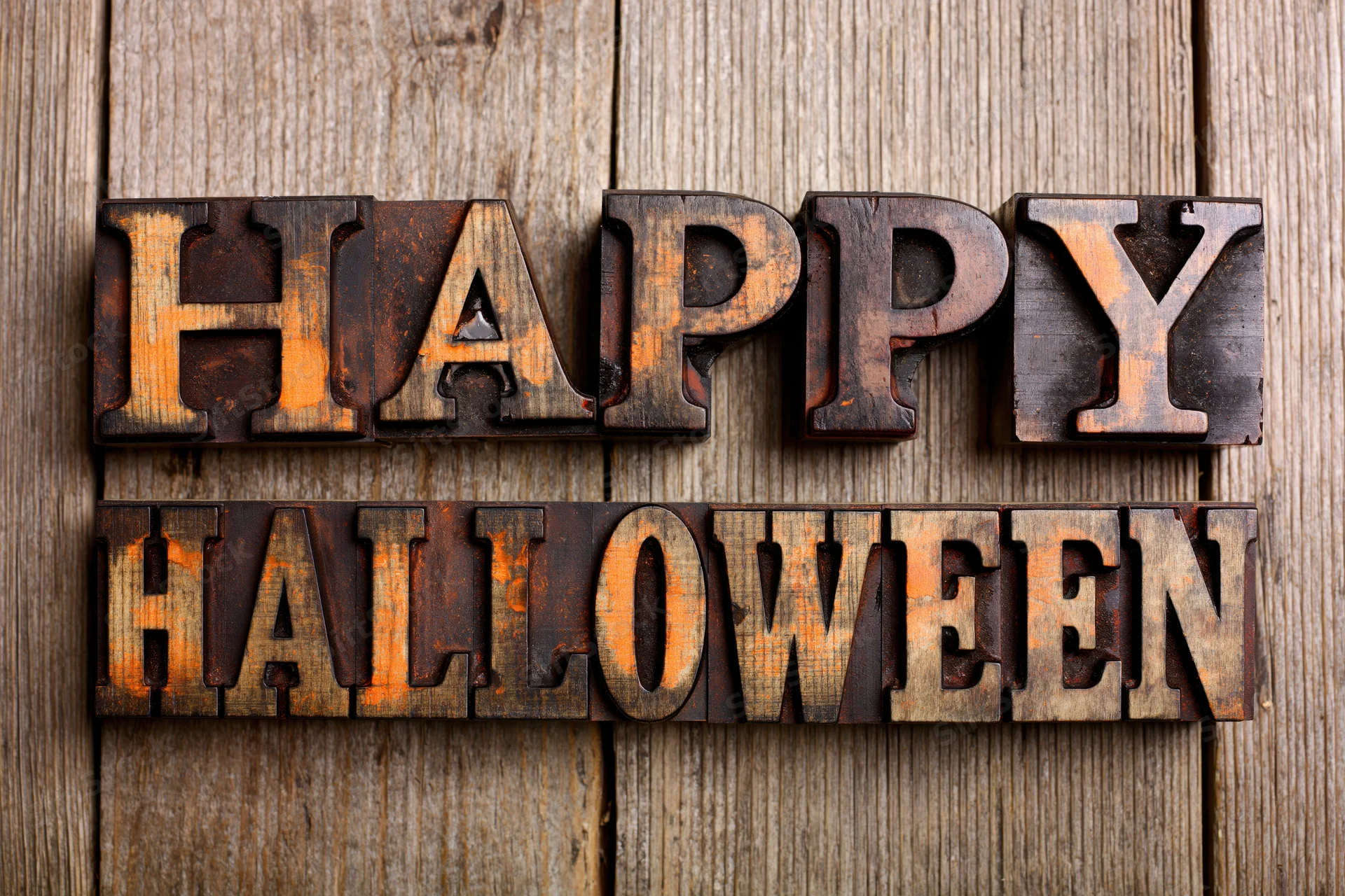 Vintage wooden letterpress blocks spelling happy halloween on a weathered wood surface