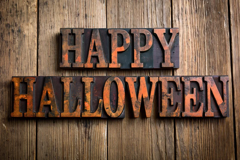 Vintage wooden letterpress blocks spelling happy halloween on a weathered wood surface
