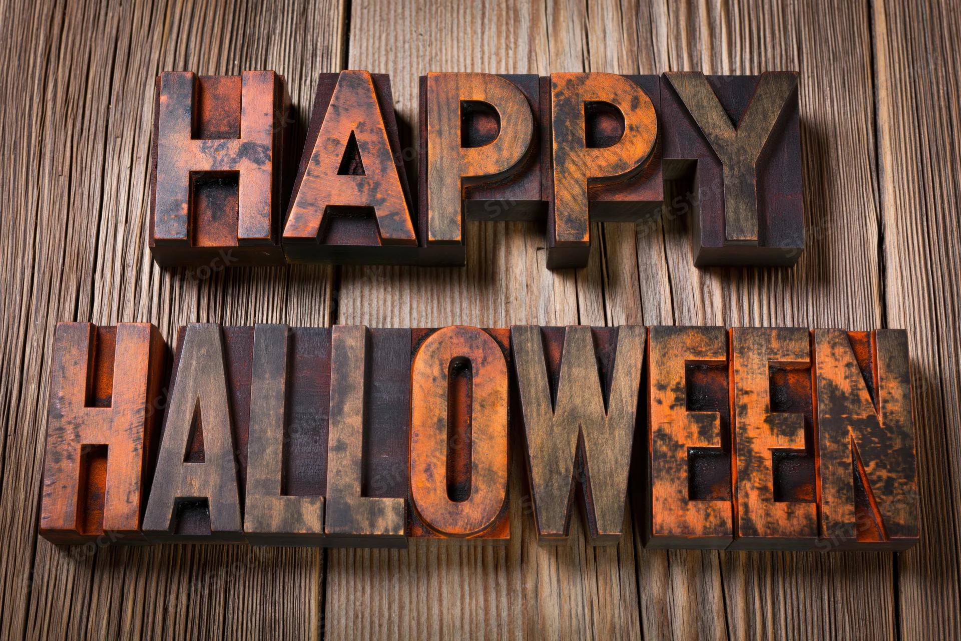 Vintage wooden letterpress blocks spelling happy halloween on a textured wood surface