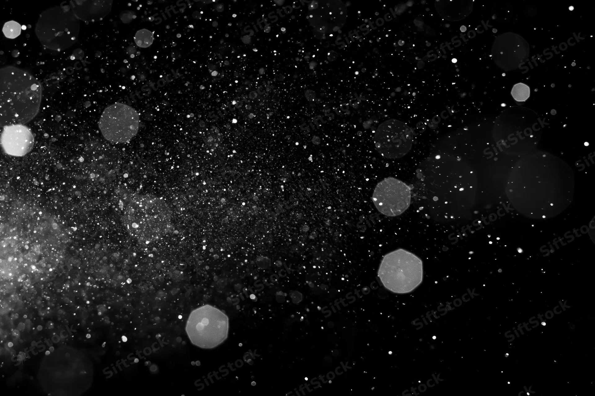 Water droplets and dust particles suspended in midair against a black background with bokeh light effects