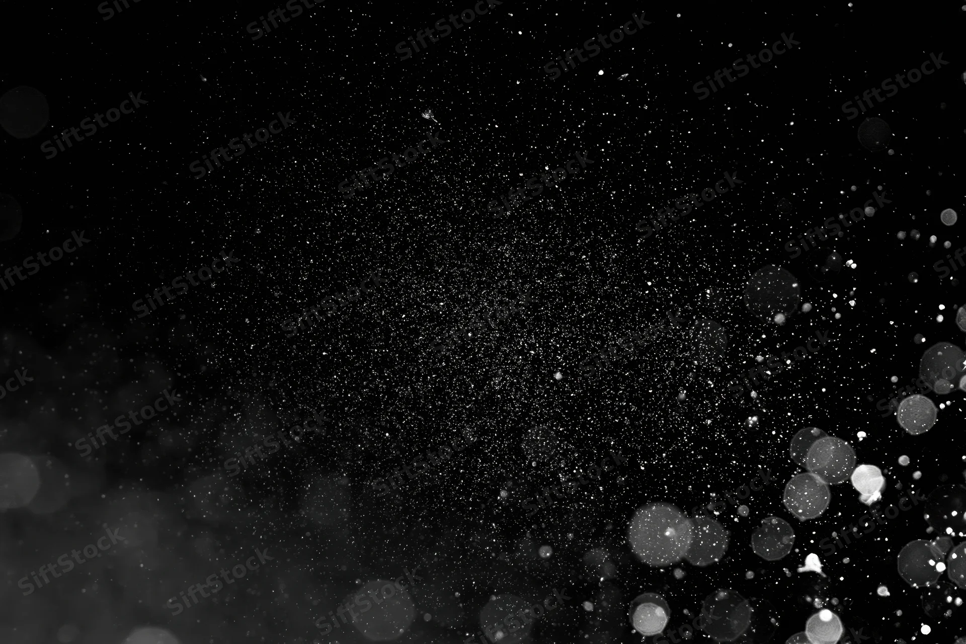 Water droplets and dust particles suspended in midair against a black background with bokeh light effects