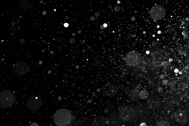 Water droplets and dust particles suspended in midair against a black background