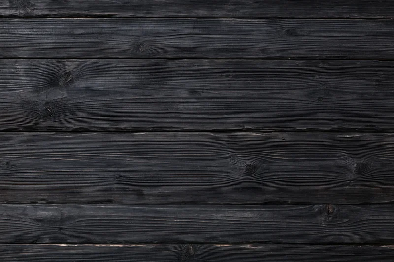 Horizontal dark charcoal wooden planks with visible grain and knots forming a textured surface