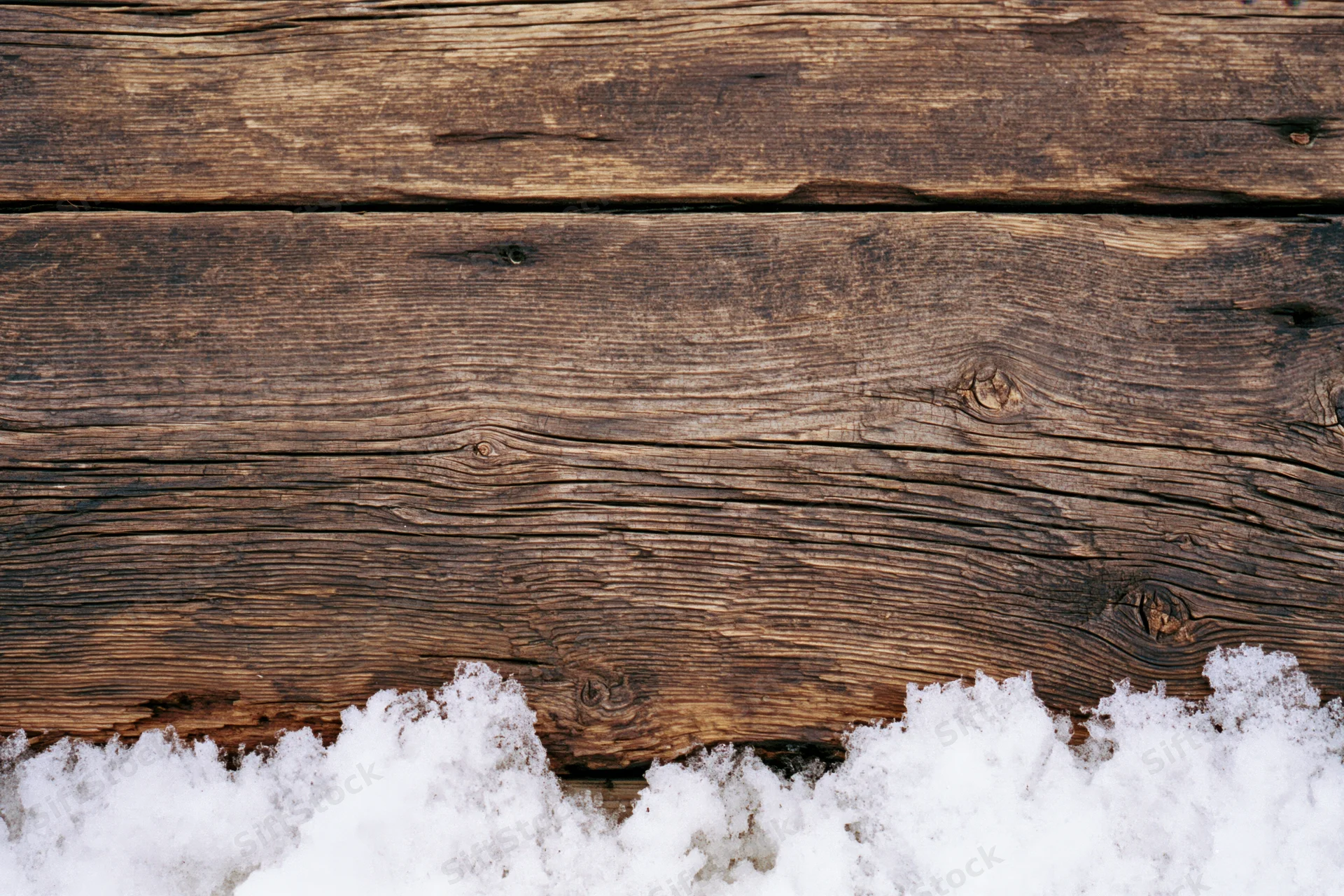 Weathered wooden planks with snow at the bottom edge, flat lay view