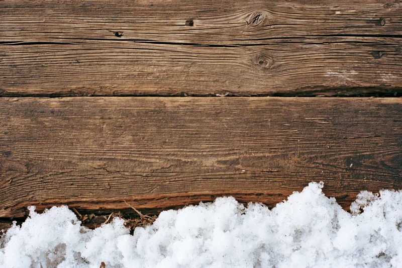 Weathered wooden planks with snow at the base, flat lay view