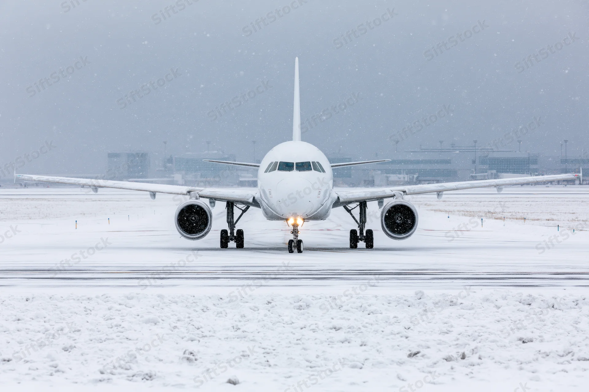 White commercial passenger jet taxiing toward camera on snow-covered runway at airport