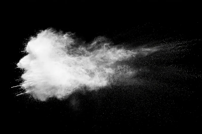White powder exploding midair against black studio background