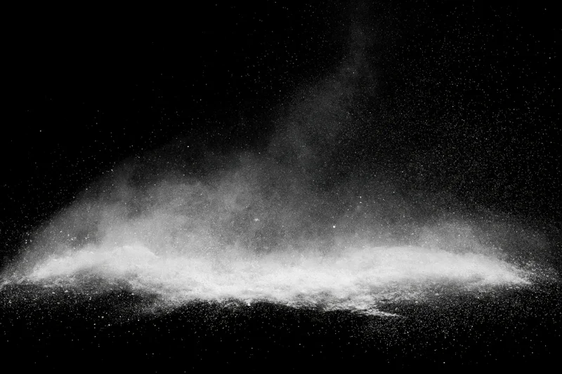 White powder exploding midair against black studio background
